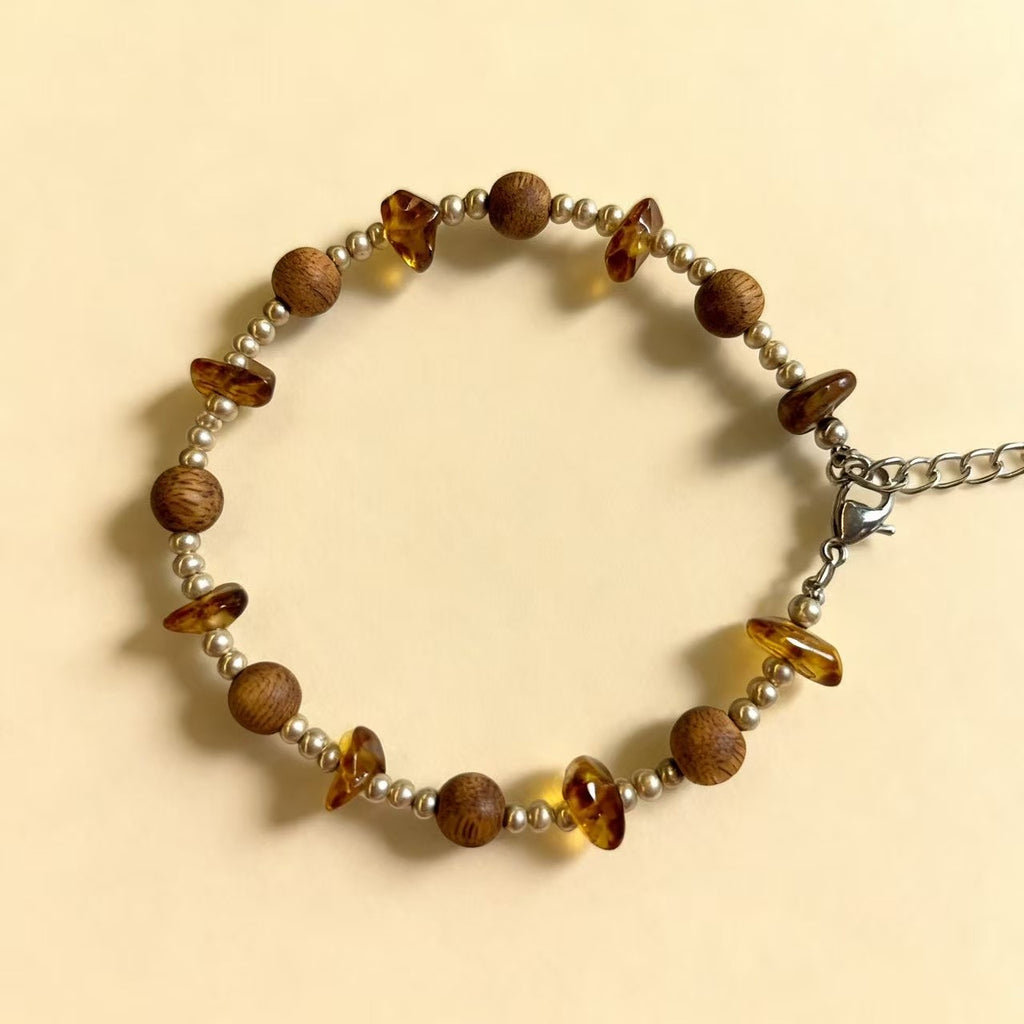 A delicate harmony of natural agarwood and warm amber-inspired stone accents.